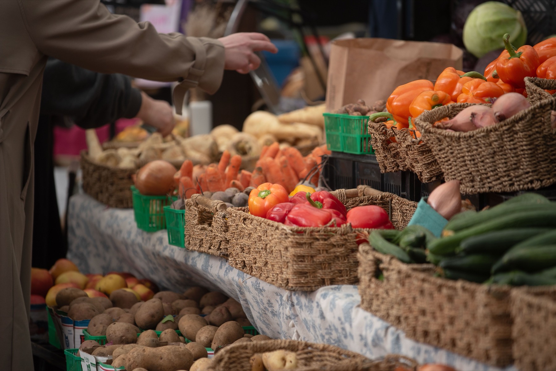 Woven baskets of fresh vegetables at an outdoor farmers market