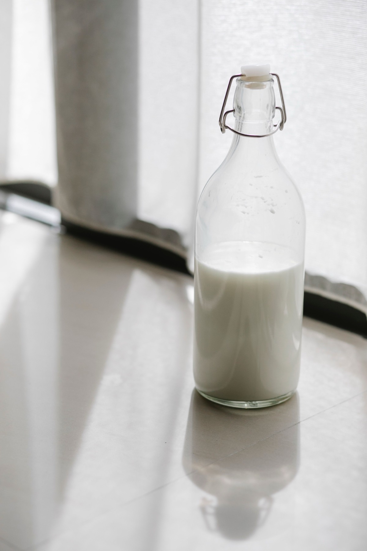Glass bottle of milk lit by window light